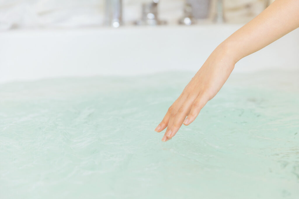 浴槽に張られたお湯を触るイメージ